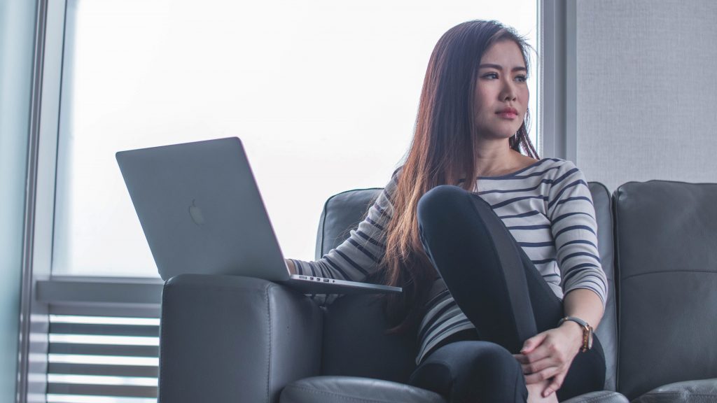 woman sitting on couch while using laptop computer