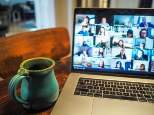 coffee cup and laptop displaying online meeting